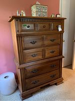 Front view showing all five drawers closed with visible knobs and handles, along with decorative details and finish.
