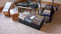 Wide shot of all the CDs in boxes and plastic trays on the floor under a table