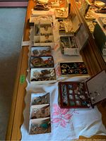 Multiple white trays on dresser holding various earrings, bracelets and pendants