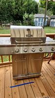Front view of Nexgrill outdoor gas grill with closed lid showing four control knobs and cabinet doors below