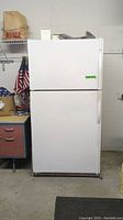 Front view of the white Kenmore refrigerator showing two-door top freezer design, standard door handles, and minor exterior wear.