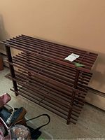 Side angle view of wood slat storage shelf unit showing three-tier shelf construction with horizontal wooden slats and vertical supports.
