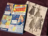 Photo of two Eaton's catalogs, one showing full colorful cover from 1953 and the other an inside page black-and-white dress illustration.