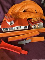 Overview of vintage Hot Wheels curved orange track sections and two plastic set pieces.