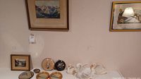 All items displayed together on wall and shelf: paintings, plates, metal dish and ceramic swans