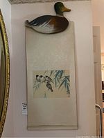 Full view of Asian wall art scroll with wood duck wall hanging mounted above.