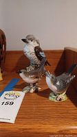 Three Beswick porcelain bird figurines displayed on wooden surface, showing front and side angles.