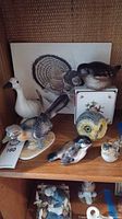 Shelf view showing all nine bird-themed items including figurines, owl planter, tin, and print