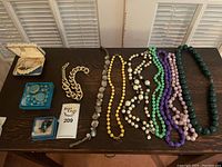 Overview of all jewelry items including necklaces, earrings, and bracelet on a wood table