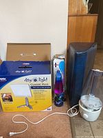 Full view of all 4 items including Carex Day-Light Classic Plus lamp in box, lava lamp, black support pillow, and white humidifier.