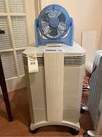 Overall view of white IQ Air purifier unit with blue fan on top, showing front and surrounding environment.