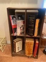 Front view of wooden antique standing bookshelf with visible two compartments holding six books.