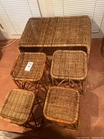 Photo showing entire wicker table along with four nesting stools arranged in front.