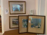 Four framed coastal prints displayed on wall and floor