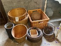 Photo showing seven wicker baskets of various shapes and sizes, including round, rectangular, tall, and small baskets with different colors and weaving styles.