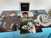Overview photo showing six vinyl album covers on a table including Rod Stewart, Culture Club, David Bowie, The Police, Blondie, and Chicago albums