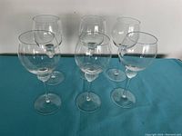 Set of six crystal wine goblets featuring a golf ball motif on the stem, arranged on a teal surface against a white background.