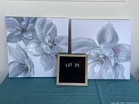 Front view of two 16-inch square floral canvas prints with grayscale flower designs on a blue surface.