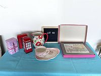 Wide shot showing all items including floral jug, phone booth bank, UK tins, teacup with saucer, placemat, and vintage print boxed in metal tin.