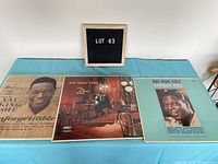 Three Nat King Cole vinyl albums placed side by side on blue cloth surface