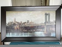 Framed print of New York City skyline with suspension bridge and buildings in sepia tones.