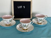Three Queen Anne Louise pattern cups and saucers on display with LOT 5 sign.