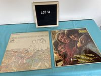 Two vinyl albums by The Monkees laid flat on turquoise cloth, one with a minimalist line drawing cover, the other with a band photo.