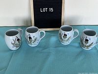 Front view of four robin egg blue cups with Scottish thistle motif arranged in a row for lot display.