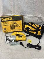 Photo of DeWALT DW317K jig saw with power cord, manual, original box, and carrying bag on display fabric background.