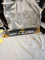 Pair of black Toughbuilt folding sawhorses shown folded, with yellow hinge supports and visible Toughbuilt branding and specifications.