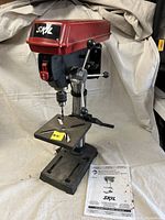 Front-left view of drill press on table showing worktable, feed lever and base