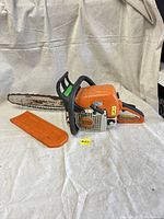 Left side view of chainsaw with bar cover removed and placed next to unit