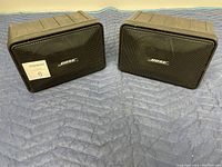 Front view of two Bose Model 101 Music Monitor speakers showing metal grills and Bose logos.