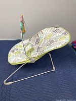 Side view of the Fisher-Price baby bouncer chair showing the fabric seat with chevron pattern and toy bar attachment with hanging toys.