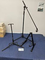 Three stands placed on blue moving blanket: two guitar stands and one microphone stand with adjustable boom arm