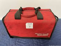 Red MasterLock branded lockout kit bag, front and top view, showing carrying handles and logo, slight dirt on fabric.