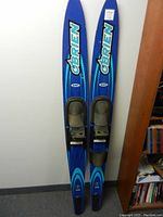 Full view of paired O'Brien Celebrity waterskis showing blue color with turquoise and black graphics, bindings attached