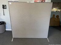 Front view of portable cloth office partition with steel frame, showing neutral gray cloth surface and steel feet.