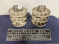 Two beige plastic rotating parts organizers each with three tiers and multiple compartments. Two long metal drill bit holders with circular holes in front.
