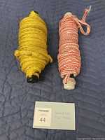 Photo showing two coiled waterski tow ropes, one solid yellow and the other red and white striped, with a small card indicating 'WATERSKI TOW ROPES' and lot number 44.