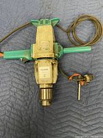Full view of the Wolf electric drill showing turquoise handles, attached power cord, and metal Jacobs chuck with key attachment.
