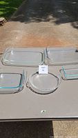 Five clear glass Pyrex cooking dishes displayed on a table, including rectangular, square, and round shapes.