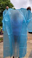 Blue disposable isolation gown held open to show full size and design