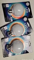 Three packaged GE LED G25 bulbs displayed, showing front with bulb shape and wattage info.