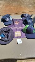 Five assorted hats and an Atlanta United FC fan flag arranged on a flat surface for display.
