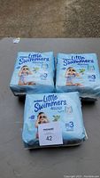 Photo showing three packs of Huggies Little Swimmers Size 3 swim pants on table