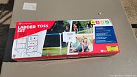 Box showing full product name 'Ladder Toss Set' and images of family playing the game outdoors.