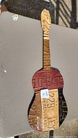Full view of guitar-shaped metal wall hanging made from license plates on a table.