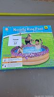 Box front showing novelty ring design inflatable pool with children playing in water.