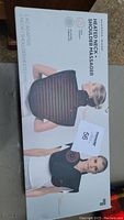 Box front showing size and product image of heated neck and shoulder massager.